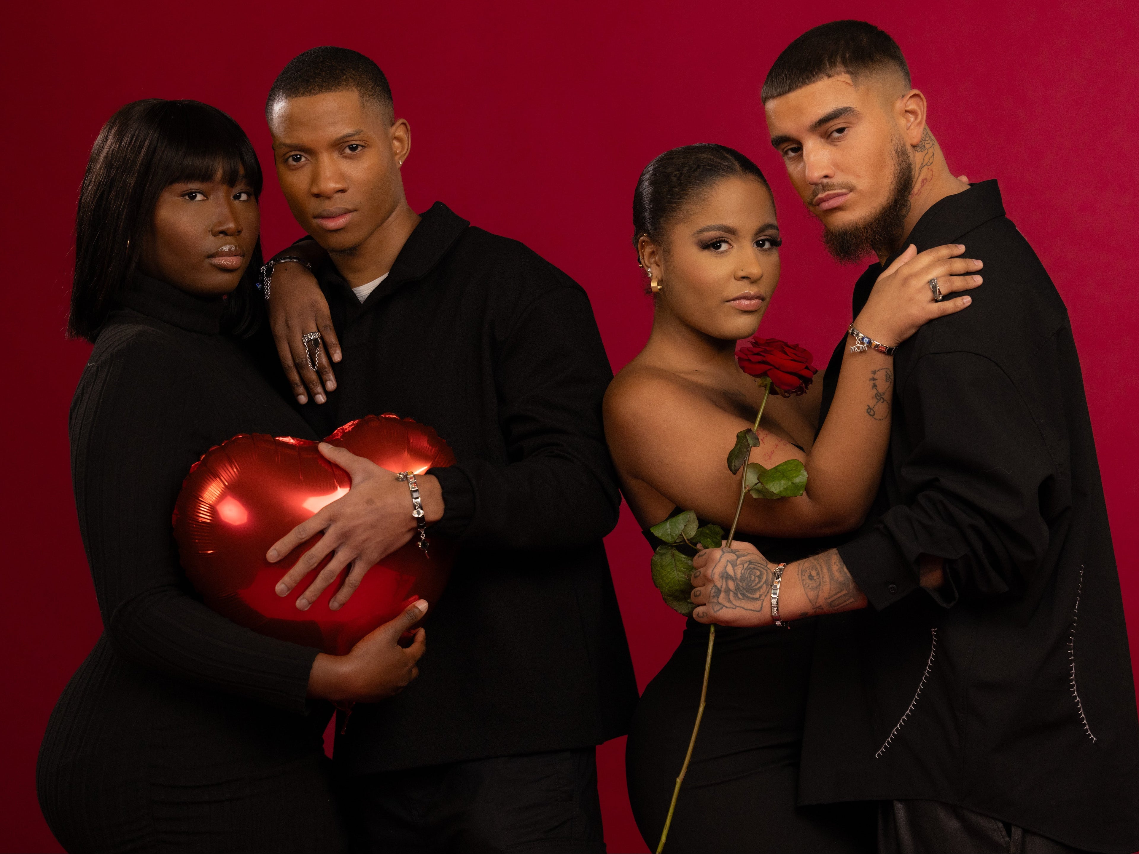 Two couples posing together against a red background, one couple holding a red heart and the other with a rose.